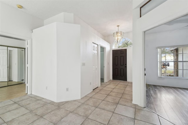 foyer featuring a textured ceiling, light tile patterned floors, and a chandelier