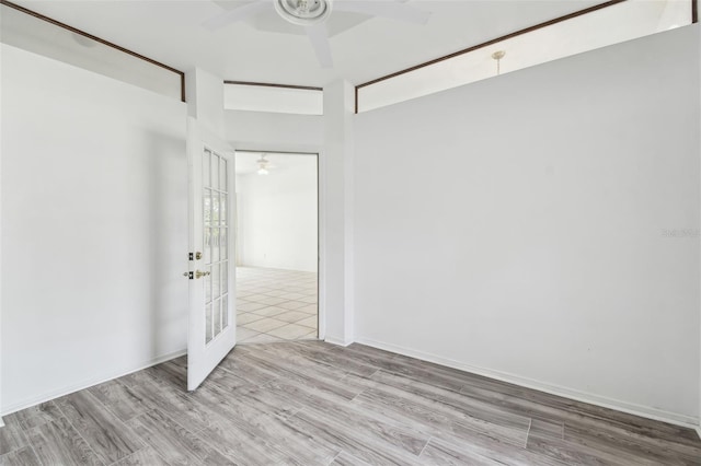 unfurnished room featuring light wood-type flooring, ceiling fan, a high ceiling, and french doors