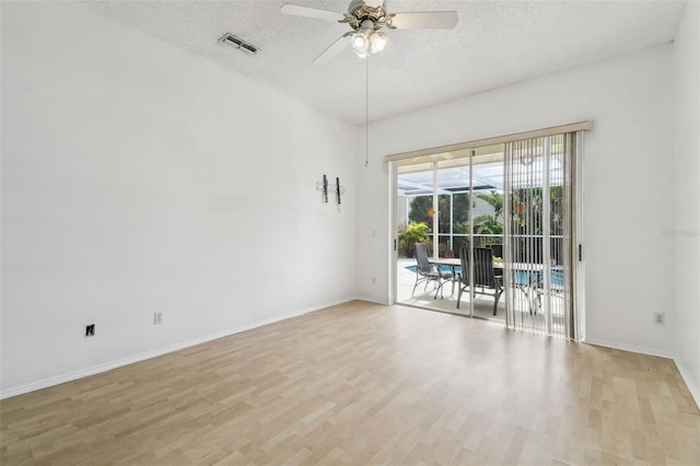 empty room featuring ceiling fan, light wood-type flooring, and a textured ceiling