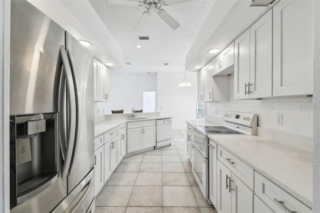 kitchen with pendant lighting, white appliances, white cabinets, sink, and light tile patterned flooring