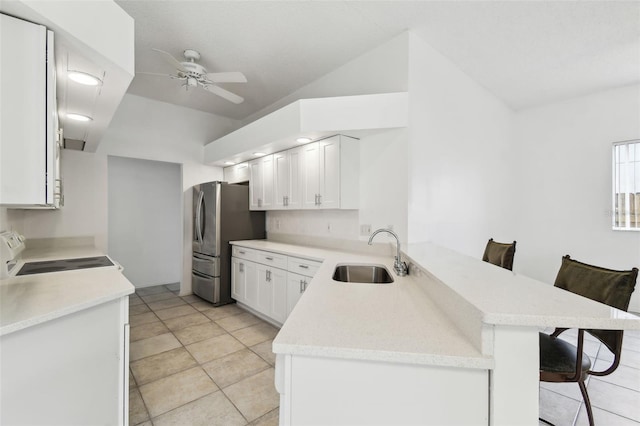 kitchen with stainless steel fridge, stove, kitchen peninsula, and a breakfast bar area