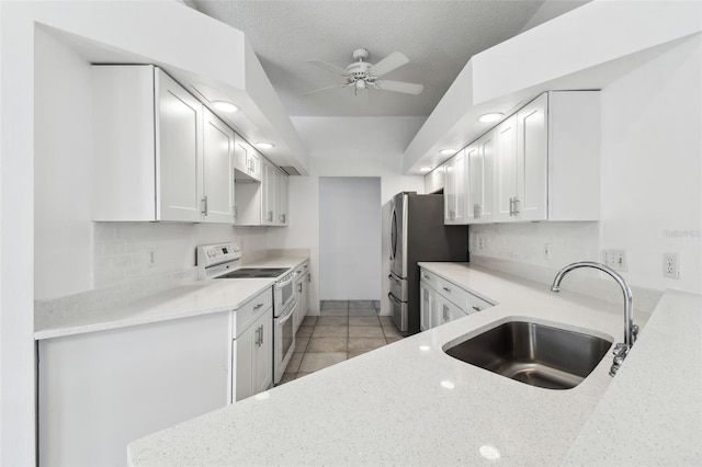 kitchen with light stone countertops, white cabinetry, double oven range, sink, and stainless steel fridge