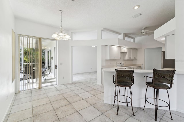 kitchen with a breakfast bar, kitchen peninsula, white cabinetry, ceiling fan with notable chandelier, and white range oven