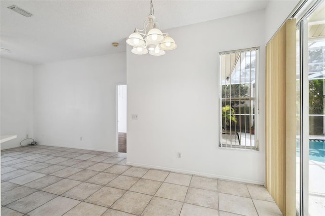 spare room featuring light tile patterned flooring and a chandelier