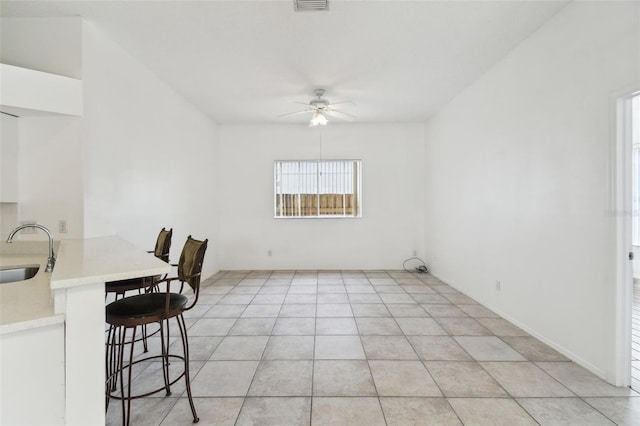 unfurnished dining area featuring ceiling fan, sink, and light tile patterned flooring