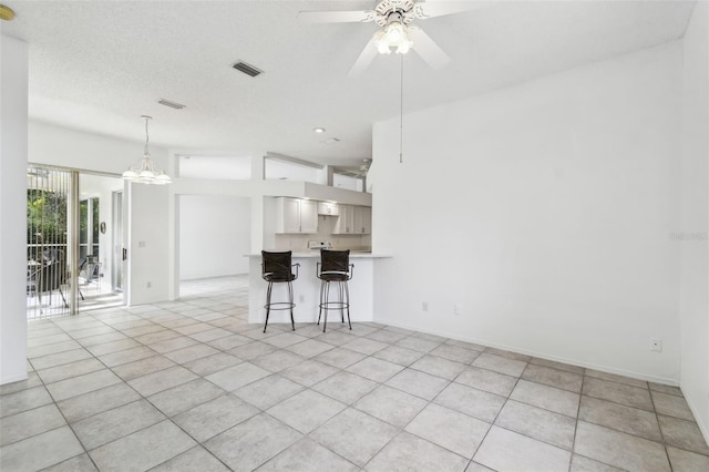 kitchen featuring kitchen peninsula, light tile patterned floors, a breakfast bar area, white cabinets, and ceiling fan with notable chandelier