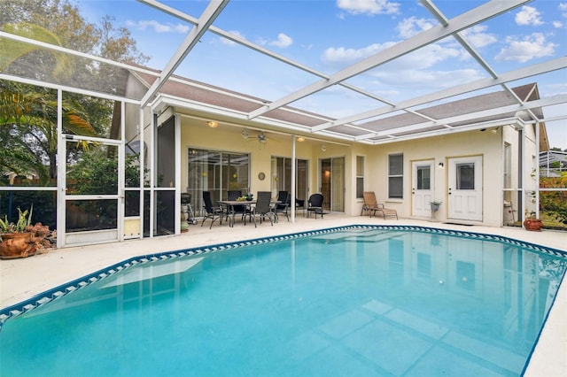 view of pool with ceiling fan, glass enclosure, and a patio area