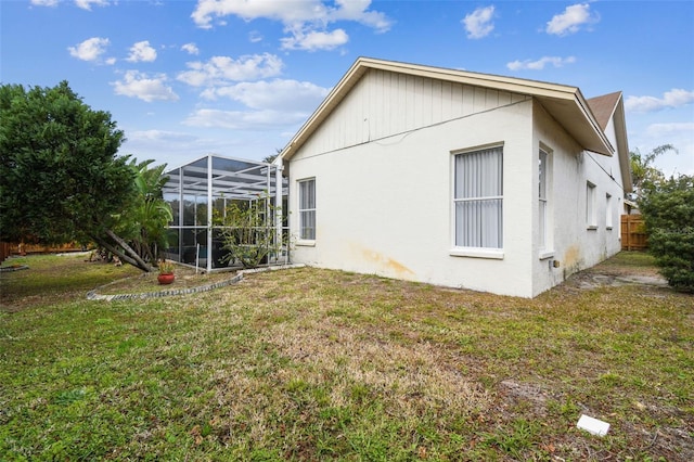 back of property with glass enclosure and a lawn