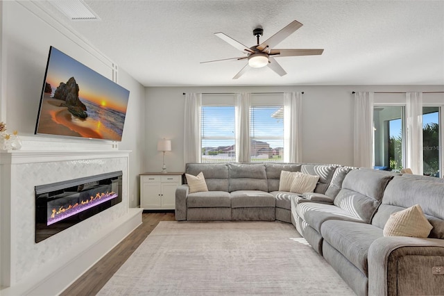 living room featuring hardwood / wood-style flooring, a textured ceiling, and ceiling fan