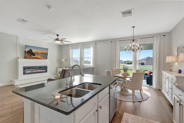 kitchen featuring white cabinets, sink, light hardwood / wood-style flooring, and a center island with sink