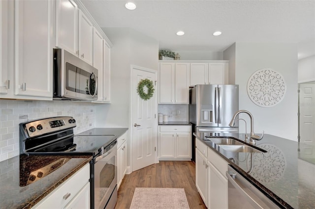 kitchen featuring dark stone countertops, stainless steel appliances, and white cabinetry