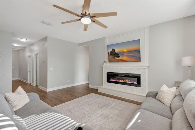 living room featuring ceiling fan, wood-type flooring, and a high end fireplace