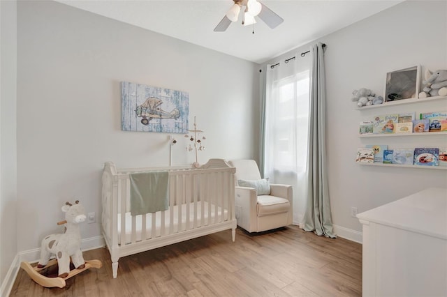 bedroom featuring ceiling fan, wood-type flooring, and a nursery area