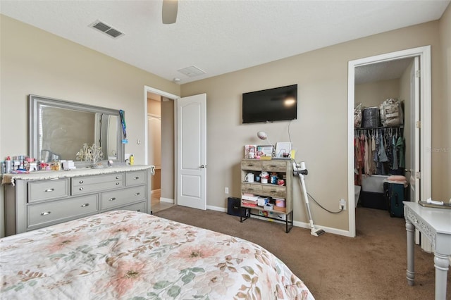 carpeted bedroom with a spacious closet, a textured ceiling, a closet, and ceiling fan