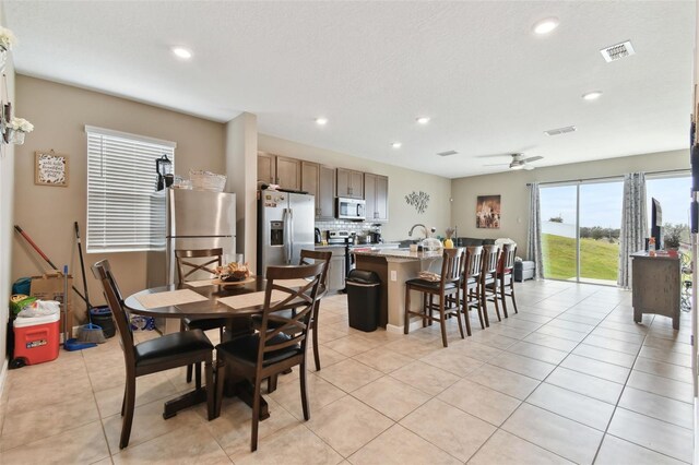 tiled dining space featuring ceiling fan and sink