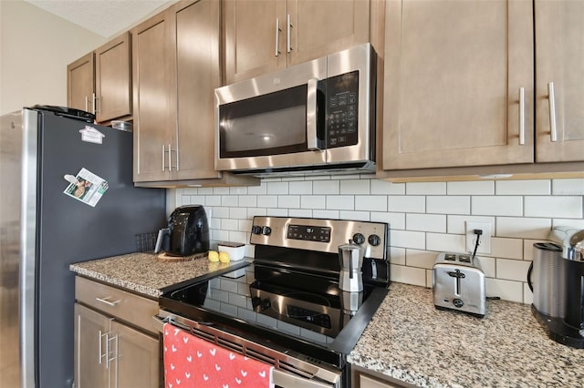 kitchen featuring decorative backsplash, light stone countertops, and stainless steel appliances