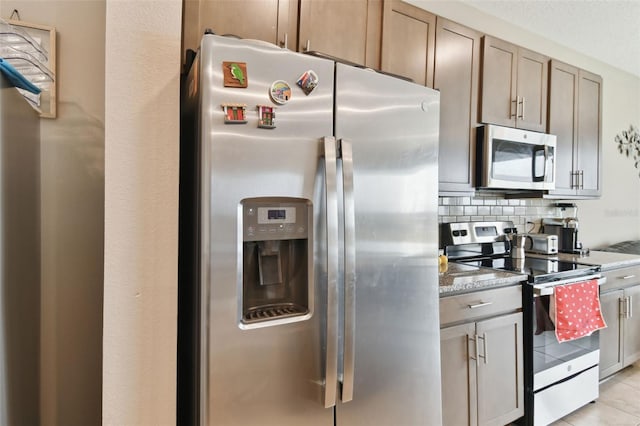 kitchen with light stone counters, backsplash, light tile patterned floors, and stainless steel appliances