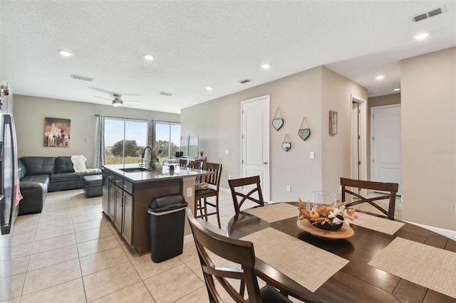 tiled dining space featuring ceiling fan, sink, and a textured ceiling