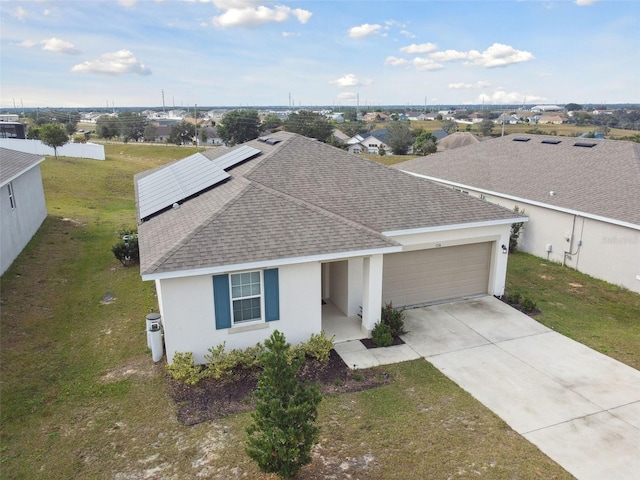 view of front of home with a garage, a front yard, and solar panels