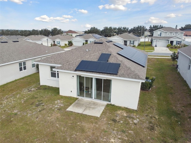 back of property featuring a yard and solar panels