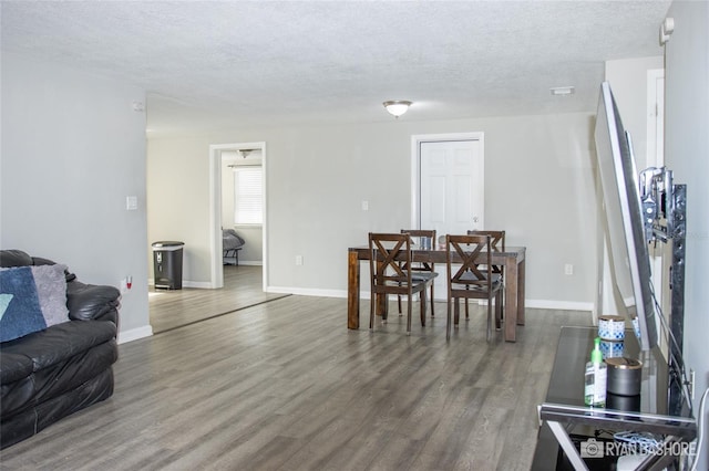 dining area with a textured ceiling and dark hardwood / wood-style flooring