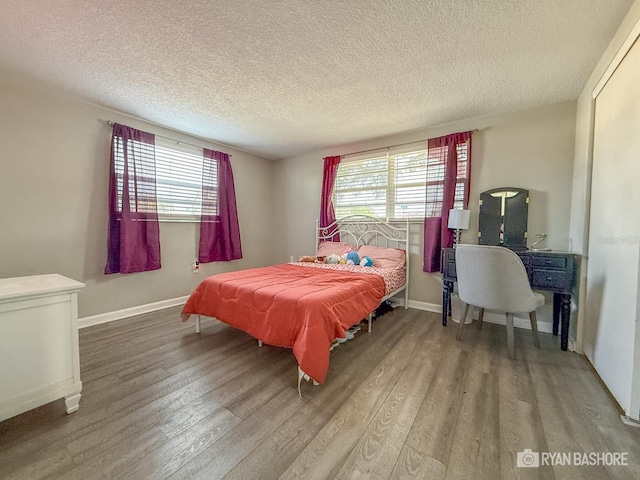 bedroom with a textured ceiling, hardwood / wood-style flooring, and multiple windows