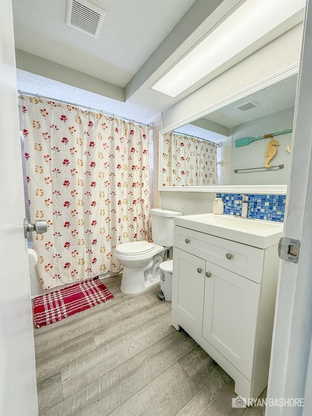 bathroom with toilet, hardwood / wood-style floors, and vanity