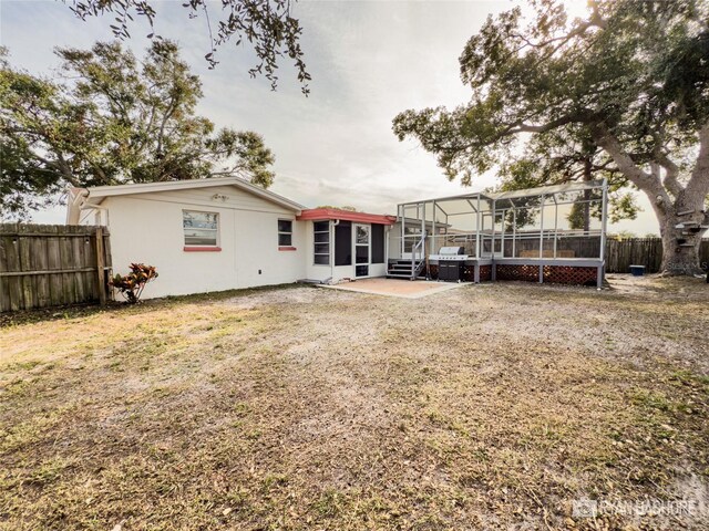 back of property featuring a lanai, a yard, and a patio