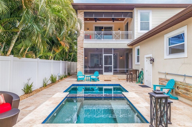 rear view of house featuring ceiling fan, a sunroom, a balcony, a swimming pool with hot tub, and a patio