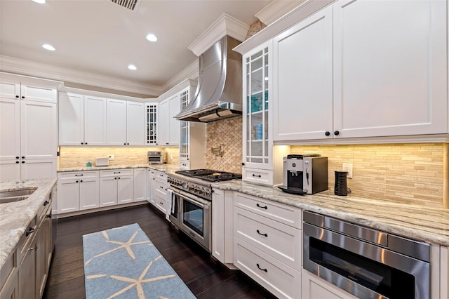 kitchen with white cabinets, wall chimney exhaust hood, stainless steel appliances, decorative backsplash, and light stone counters