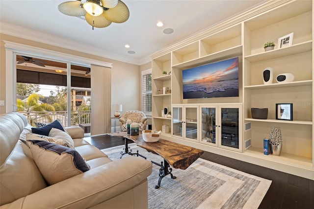 living room featuring ceiling fan, crown molding, dark hardwood / wood-style floors, and built in shelves