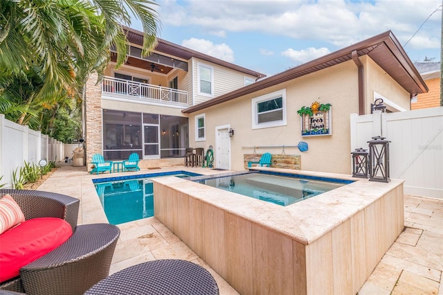 view of pool with an in ground hot tub, a patio area, and a sunroom