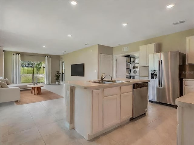 kitchen featuring light tile patterned floors, white cabinetry, a center island with sink, appliances with stainless steel finishes, and sink