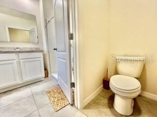 bathroom with toilet, vanity, and tile patterned flooring