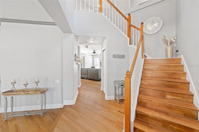 stairway with hardwood / wood-style flooring, a high ceiling, and ceiling fan