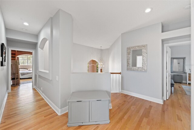 hallway featuring a chandelier and light hardwood / wood-style flooring