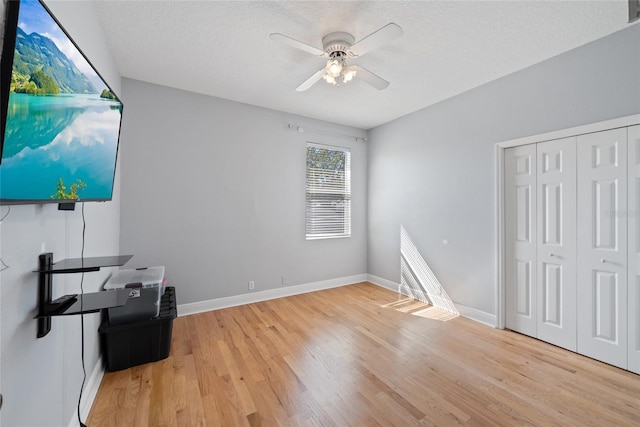 interior space featuring ceiling fan, a textured ceiling, light hardwood / wood-style floors, and a closet