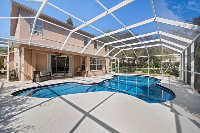 view of swimming pool featuring a patio, ceiling fan, and glass enclosure