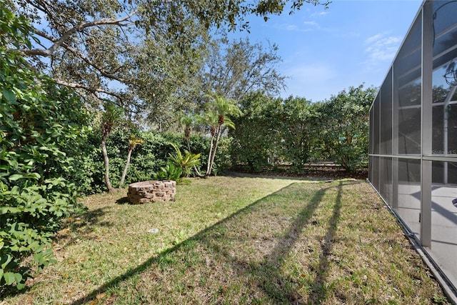 view of yard with a lanai and an outdoor fire pit