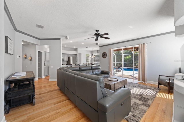 living room with ceiling fan, crown molding, light hardwood / wood-style floors, and a textured ceiling