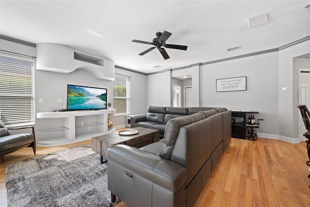 living room featuring ornamental molding, ceiling fan, a textured ceiling, and light hardwood / wood-style flooring