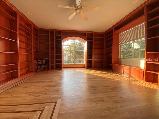 empty room with ceiling fan, built in features, and light hardwood / wood-style flooring