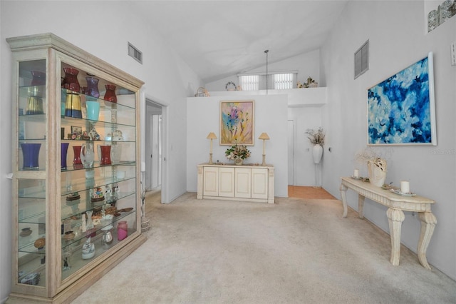 misc room with high vaulted ceiling and light colored carpet