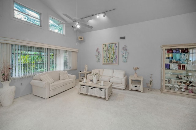 carpeted living room with ceiling fan, a wealth of natural light, track lighting, and high vaulted ceiling