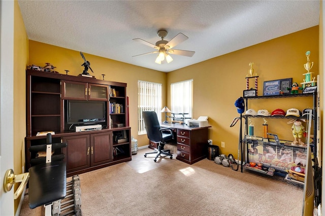 office area with light carpet, ceiling fan, and a textured ceiling