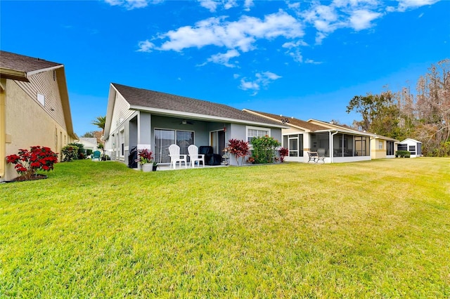 back of property featuring a lawn, a patio area, and a sunroom