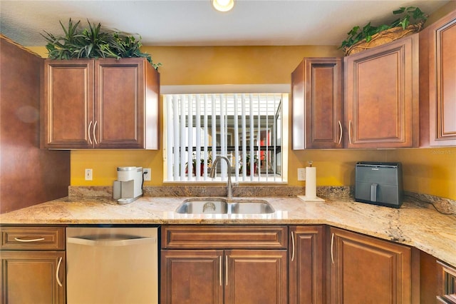 kitchen with light stone countertops, dishwasher, and sink