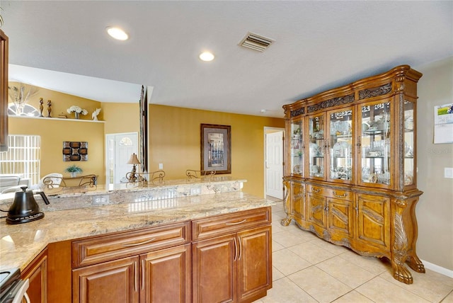 kitchen featuring light tile patterned floors, range, and light stone countertops