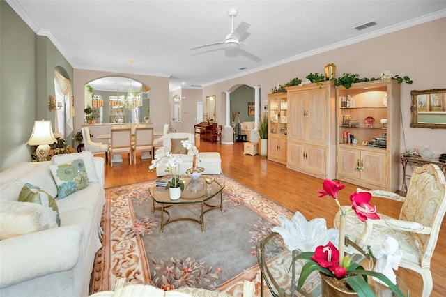 living room with ornamental molding, ceiling fan with notable chandelier, and light hardwood / wood-style flooring