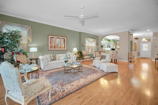 living room with ceiling fan, a healthy amount of sunlight, light wood-type flooring, and ornamental molding